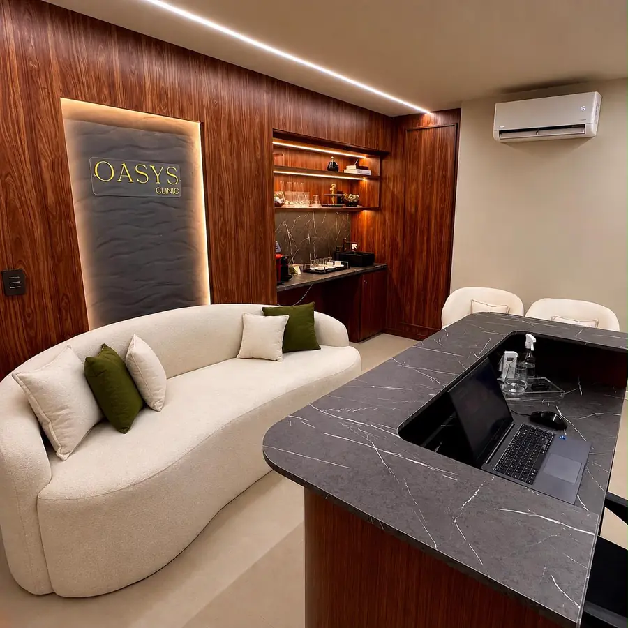 Recepção da Oasys Clinic: sofá curvo, painel de madeira iluminado e bancada de mármore